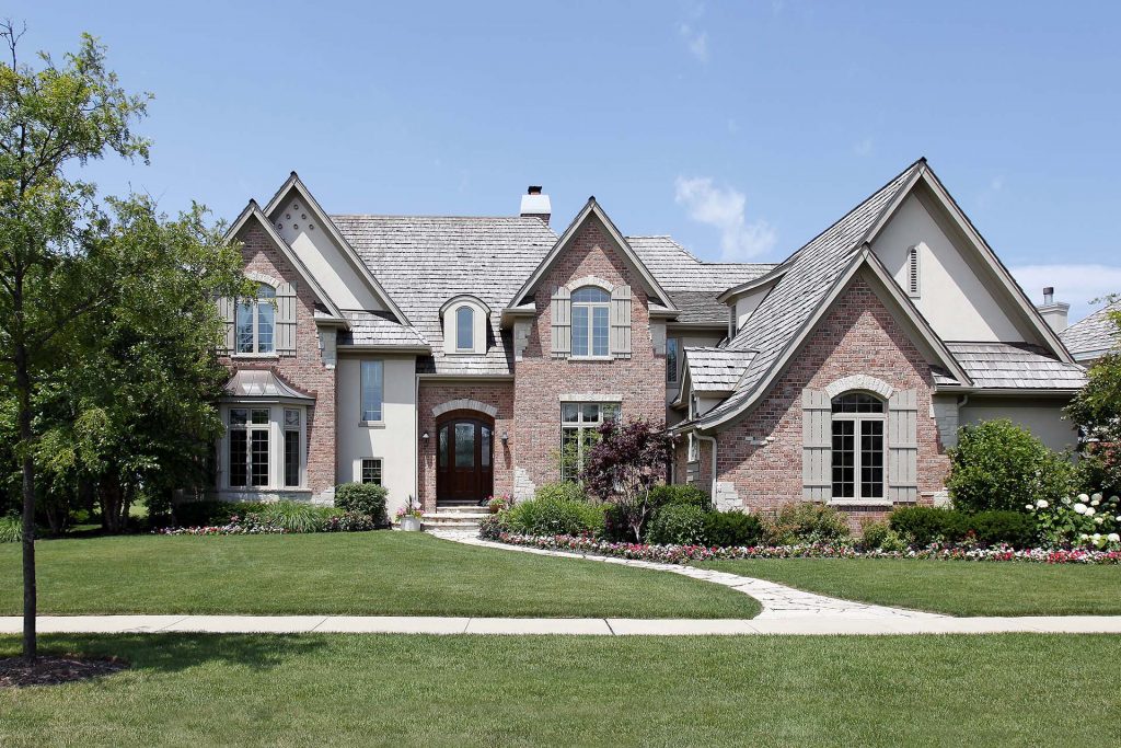 Large brick home with gray wood shake roof 