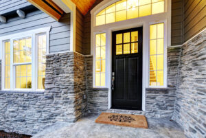 Front covered porch design boasts stone siding which creates immense curb appeal of luxurious home.