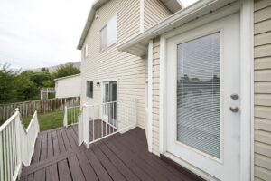 Back patio of a home with white framed doors and tan siding