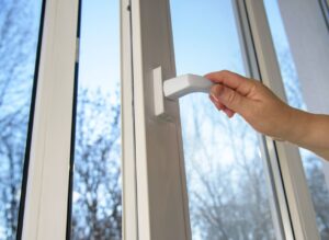 Person opening a casement window with white frames