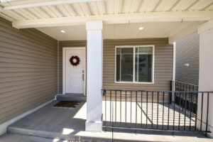 Front porch of a home with vinyl siding and metal railing
