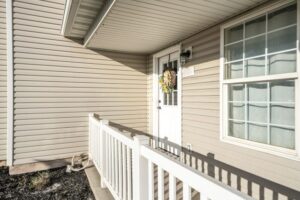 Tan vinyl siding on a home with a white fence